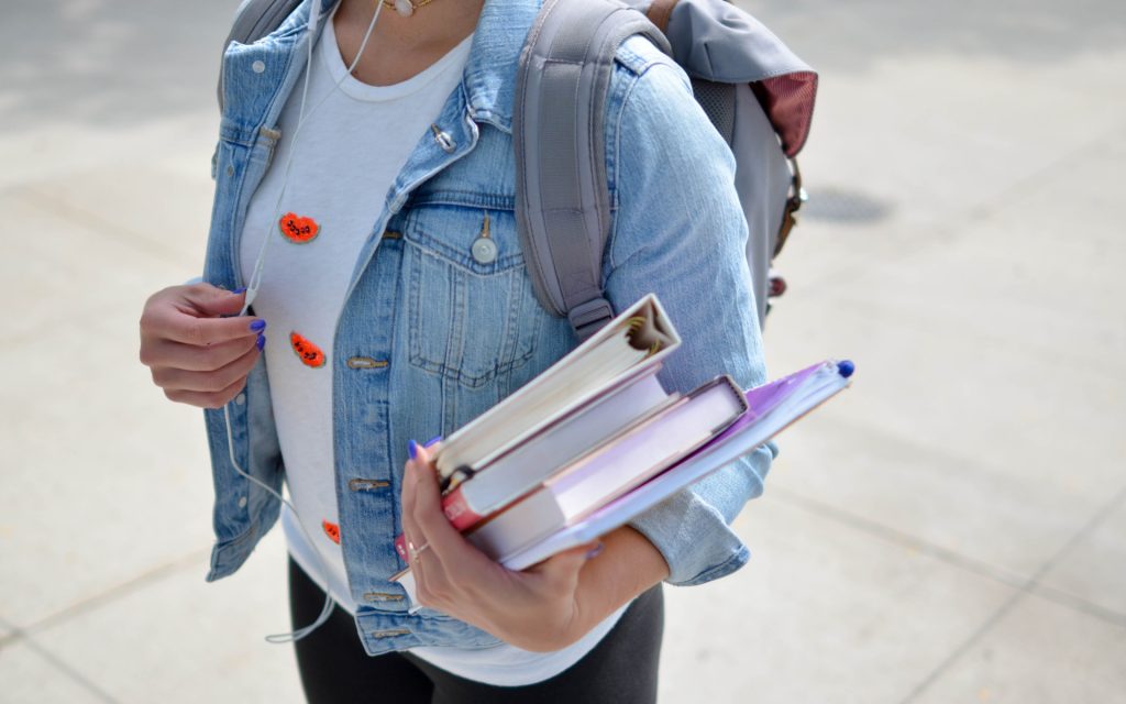 Woman Wearing A Blue Denim Jacket Holding Some School Books